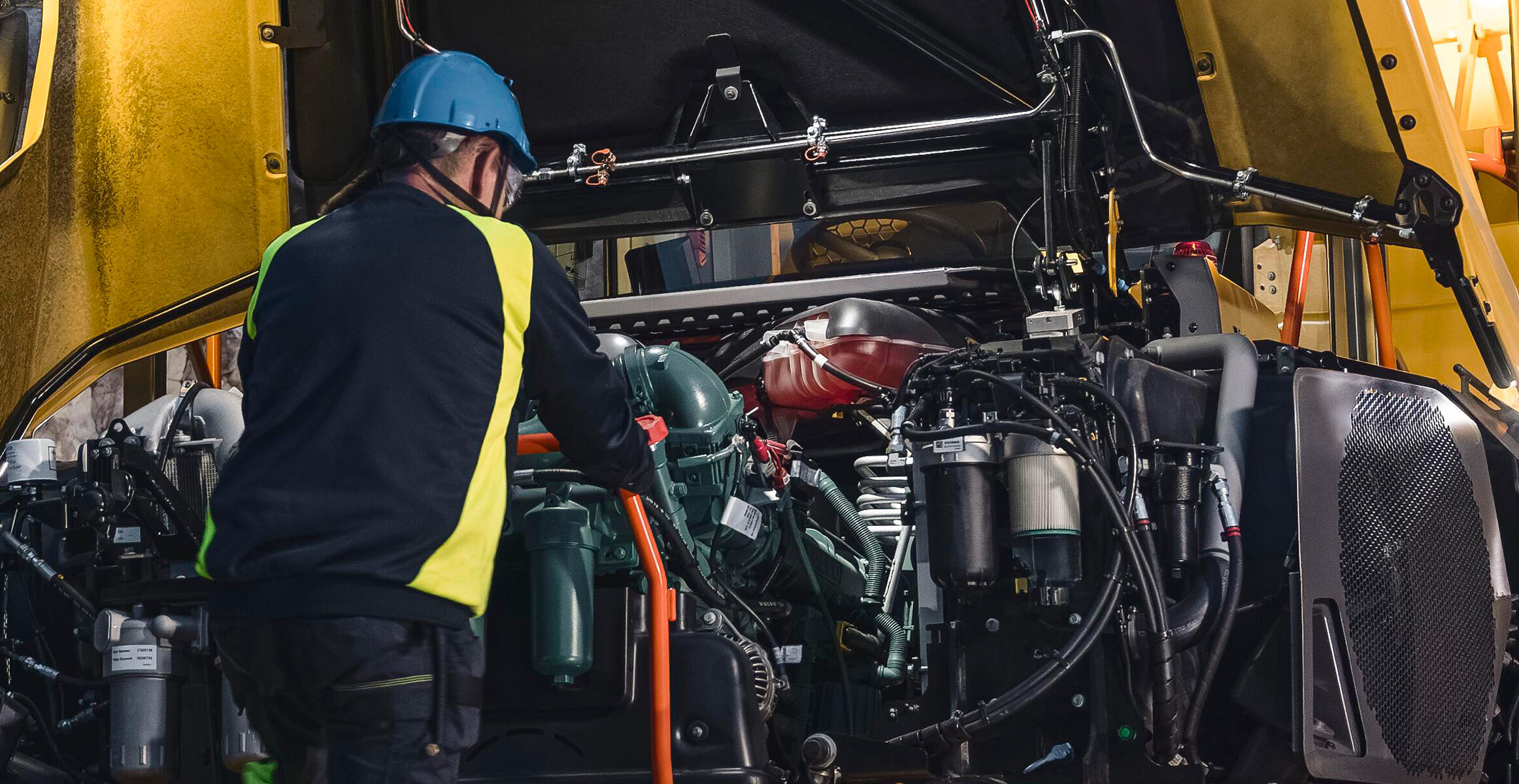 Volvo technician working inside the engine compartment of a Volvo Articulated Hauler.
