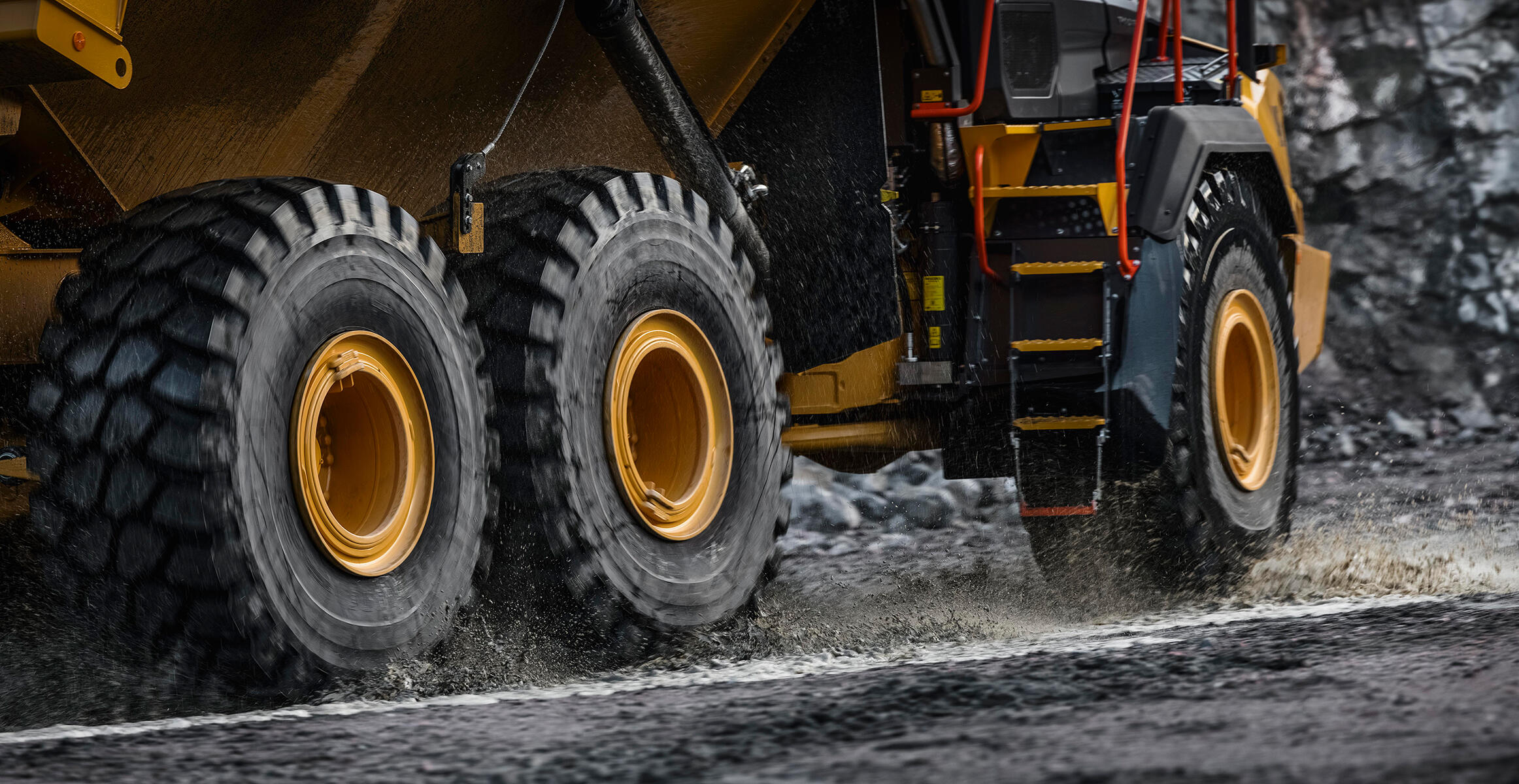 The tires of a Volvo Articulated Hauler are driving through wet and muddy conditions.
