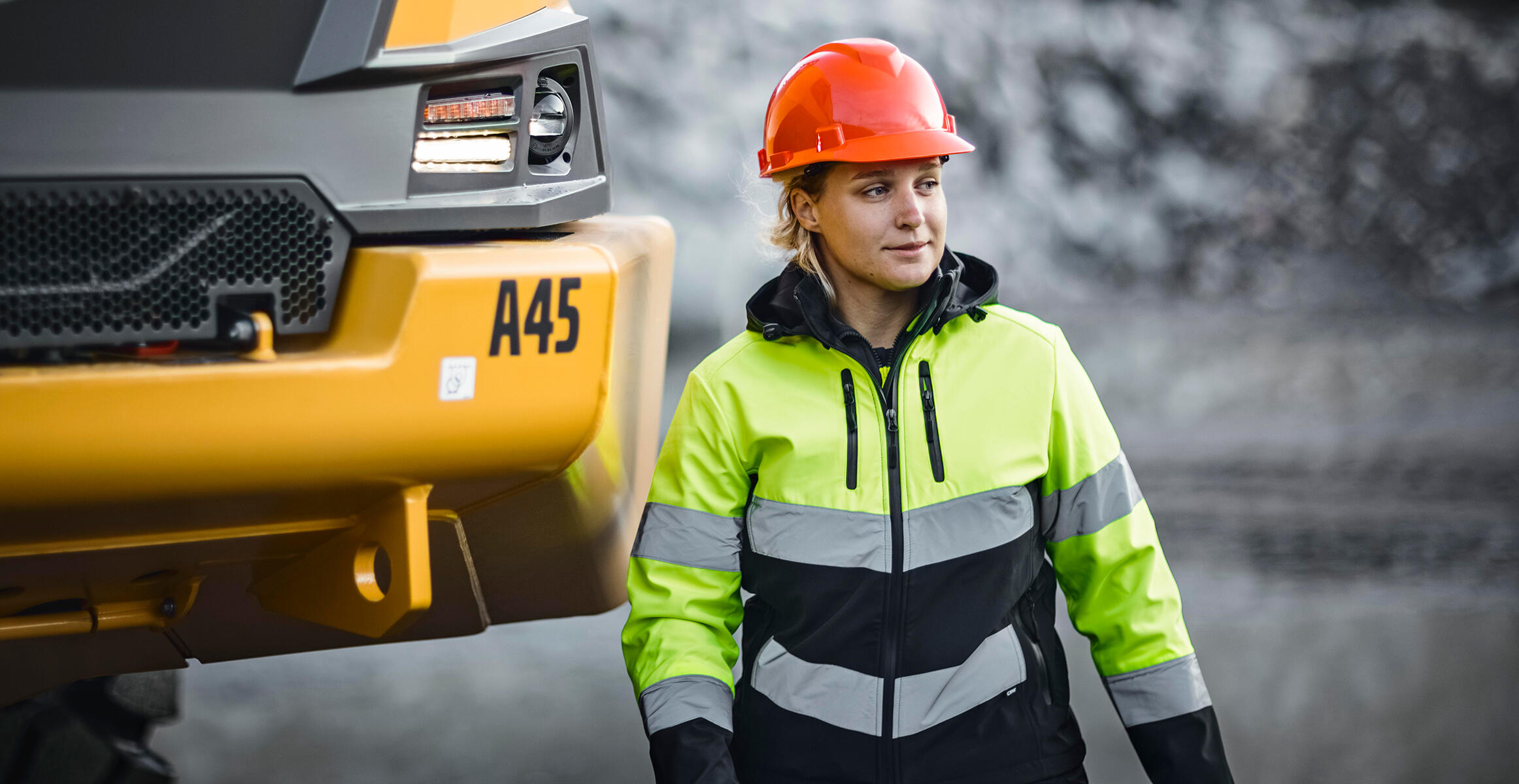 An operator stands next to the front of an A45 Volvo Articulated Hauler