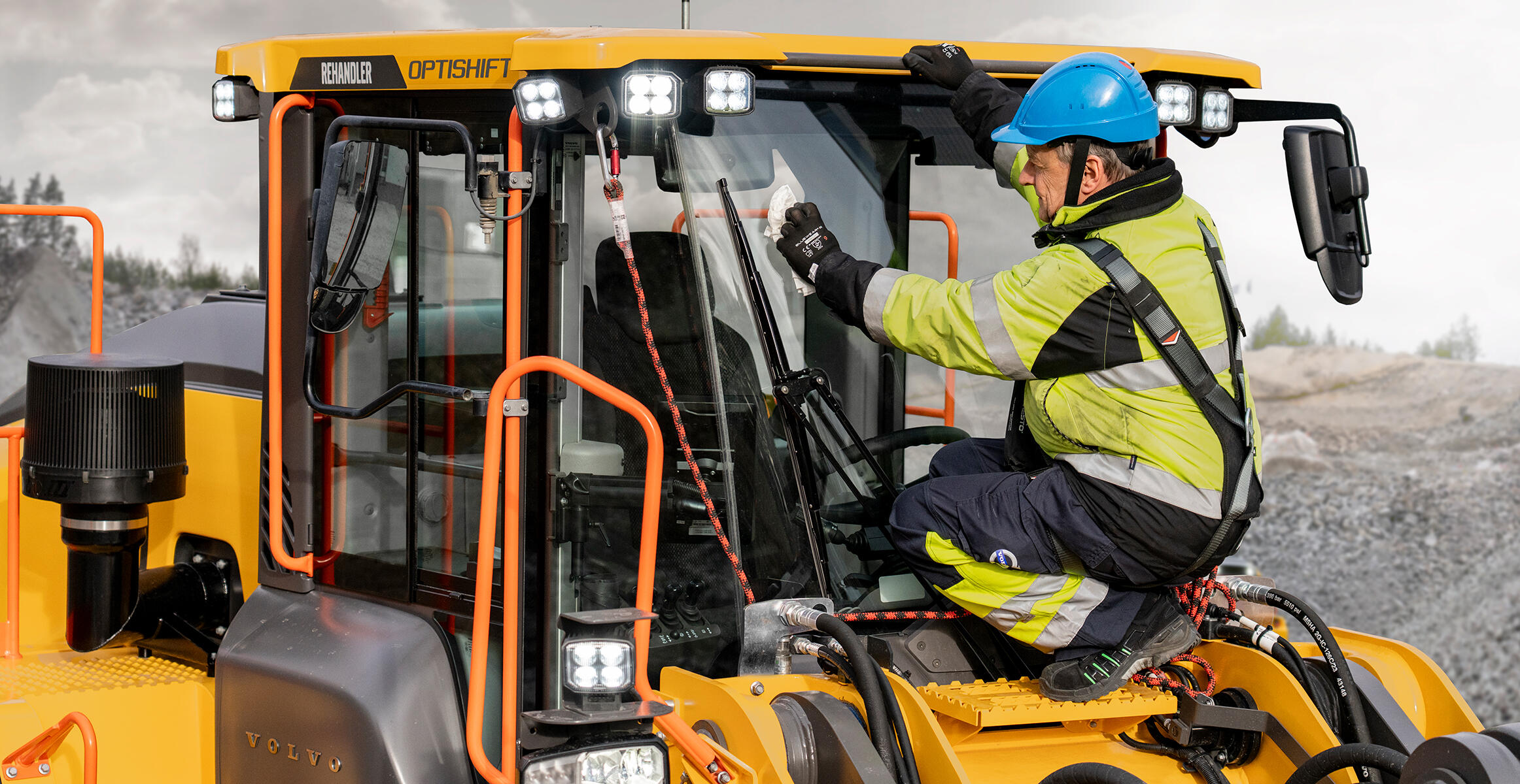 Technician stands on service platform working on Volvo wheel loader