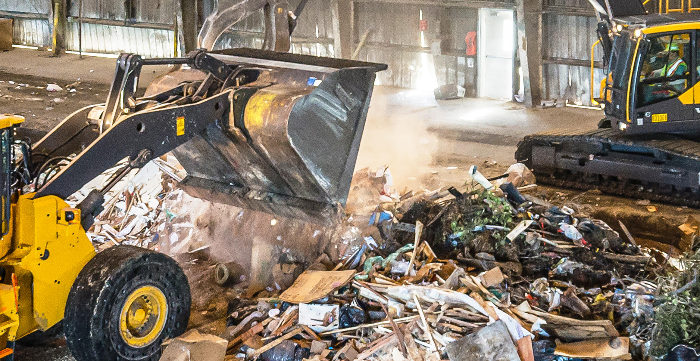 Volvo waste handler moving dust in a recycling factory site.