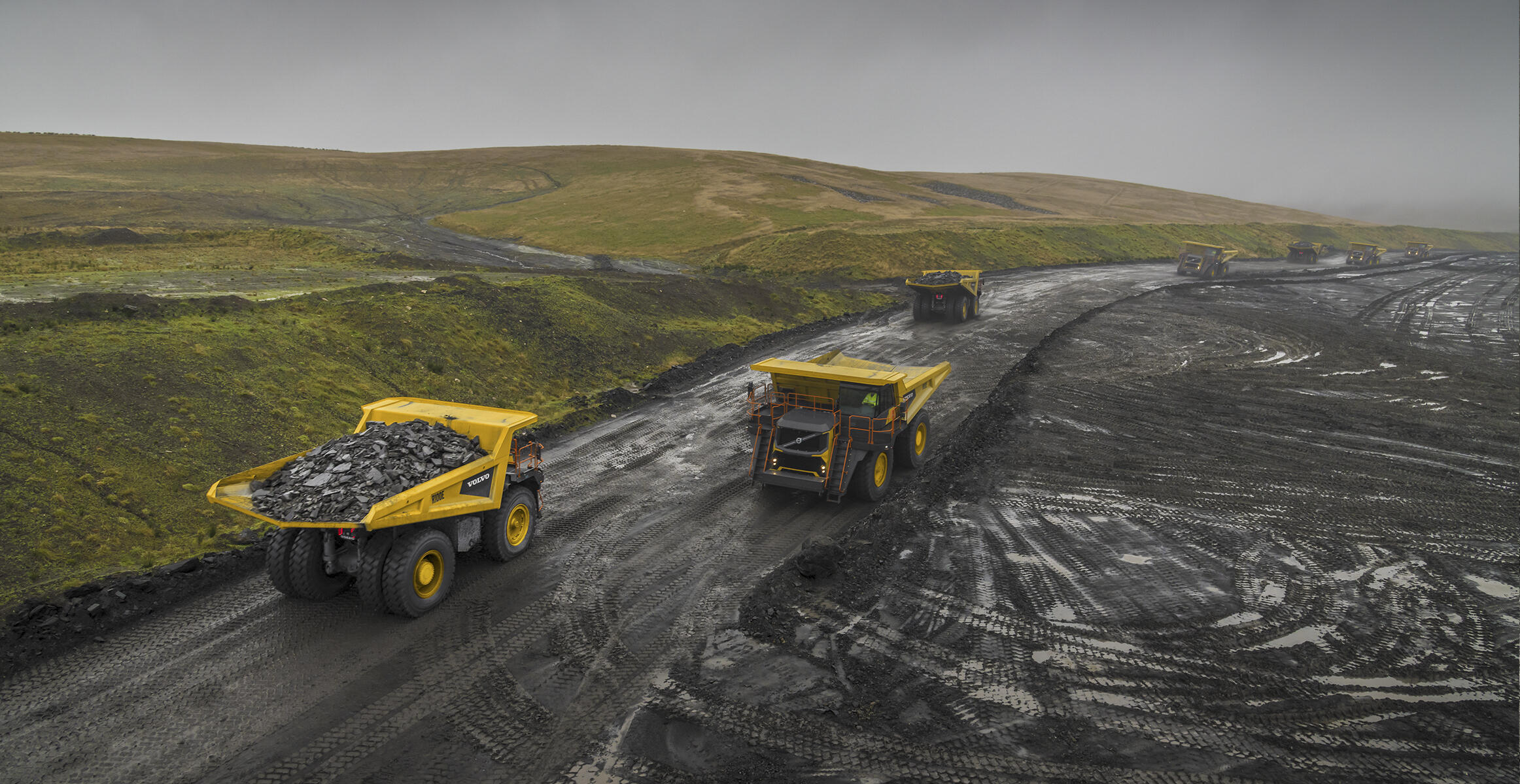 七辆沃尔沃R100矿用卡车在暴雨中作业，无惧严苛作业环境。